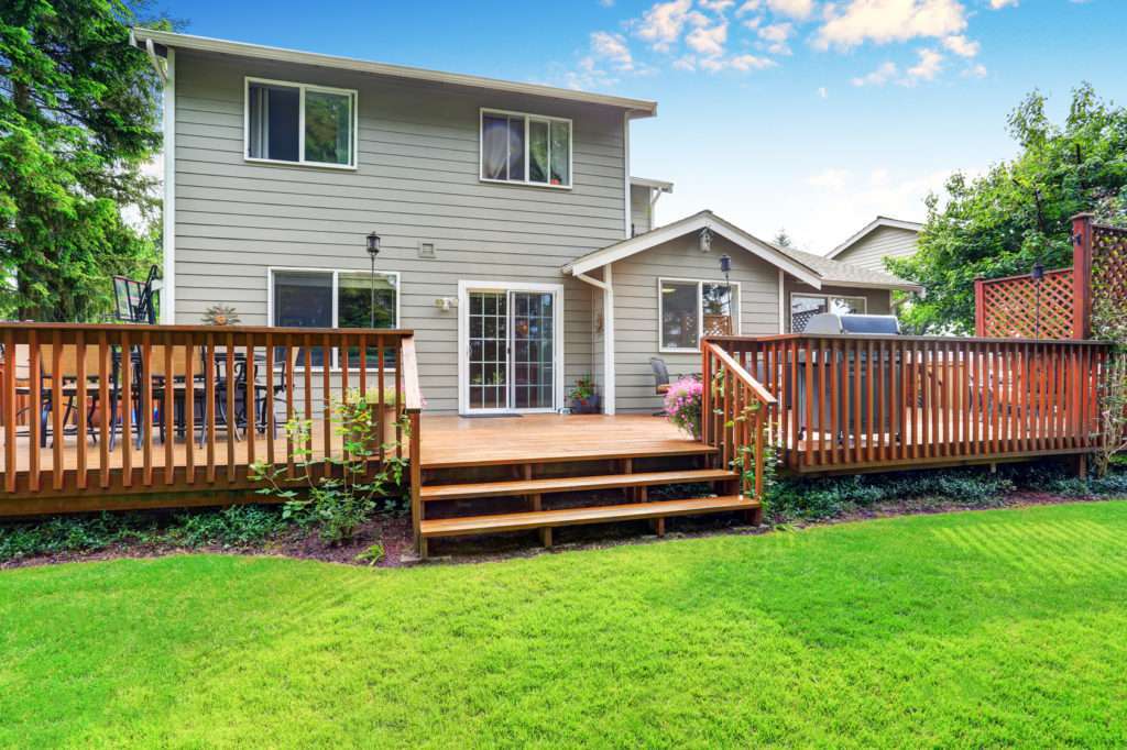 Back yard house exterior with spacious wooden deck with patio area and attached pergola. Northwest, USA